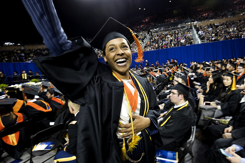 Smiling student snapping a selife at graduation