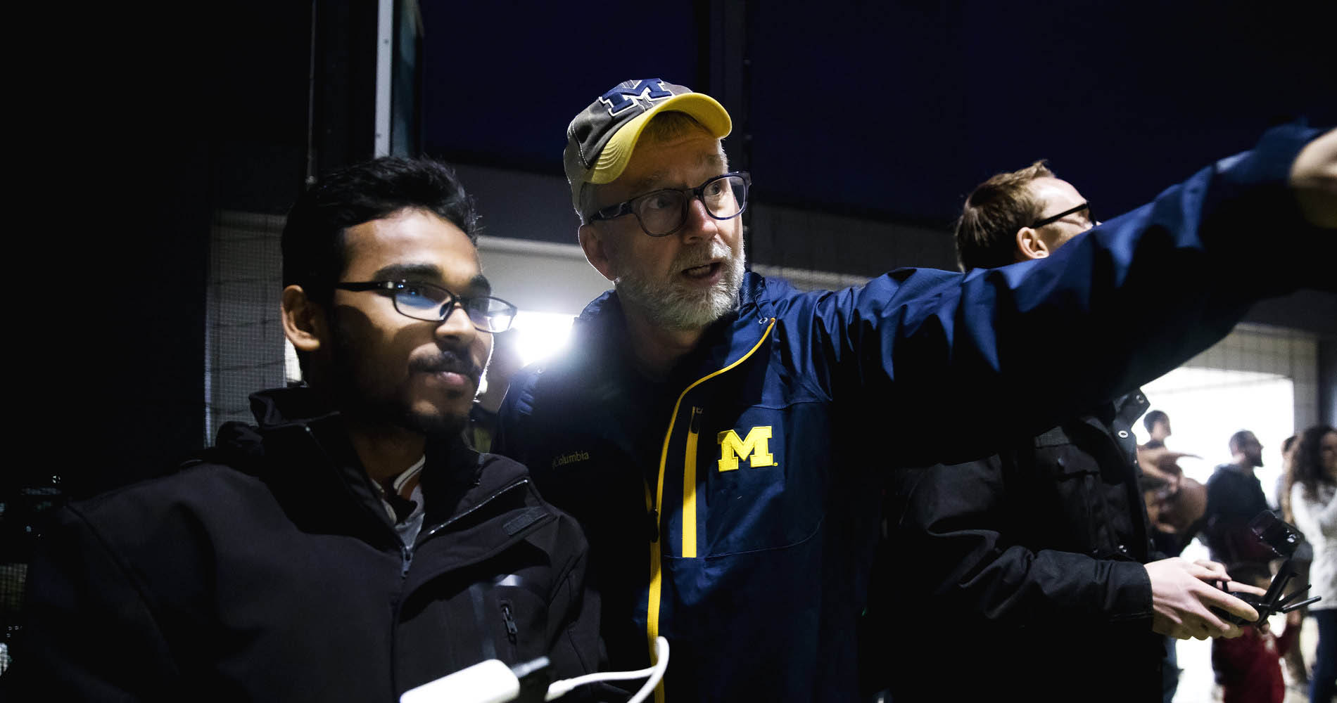 A professor coaches a student on how to fly a drone.