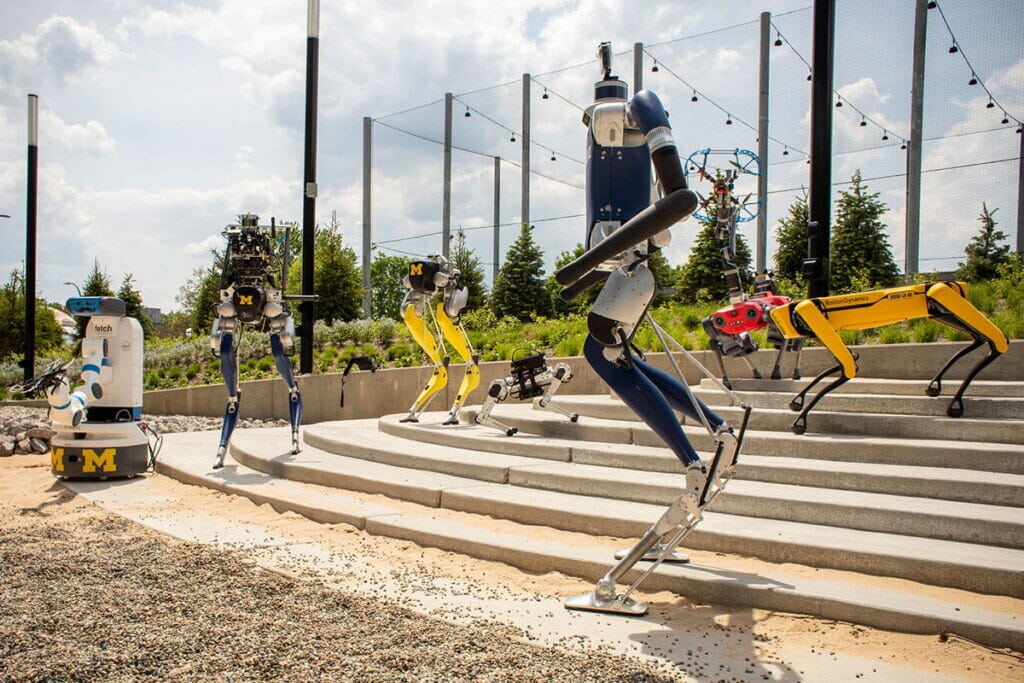 Numerous robots are organized to showcase the Robot Garden near the Robotics Institute building.