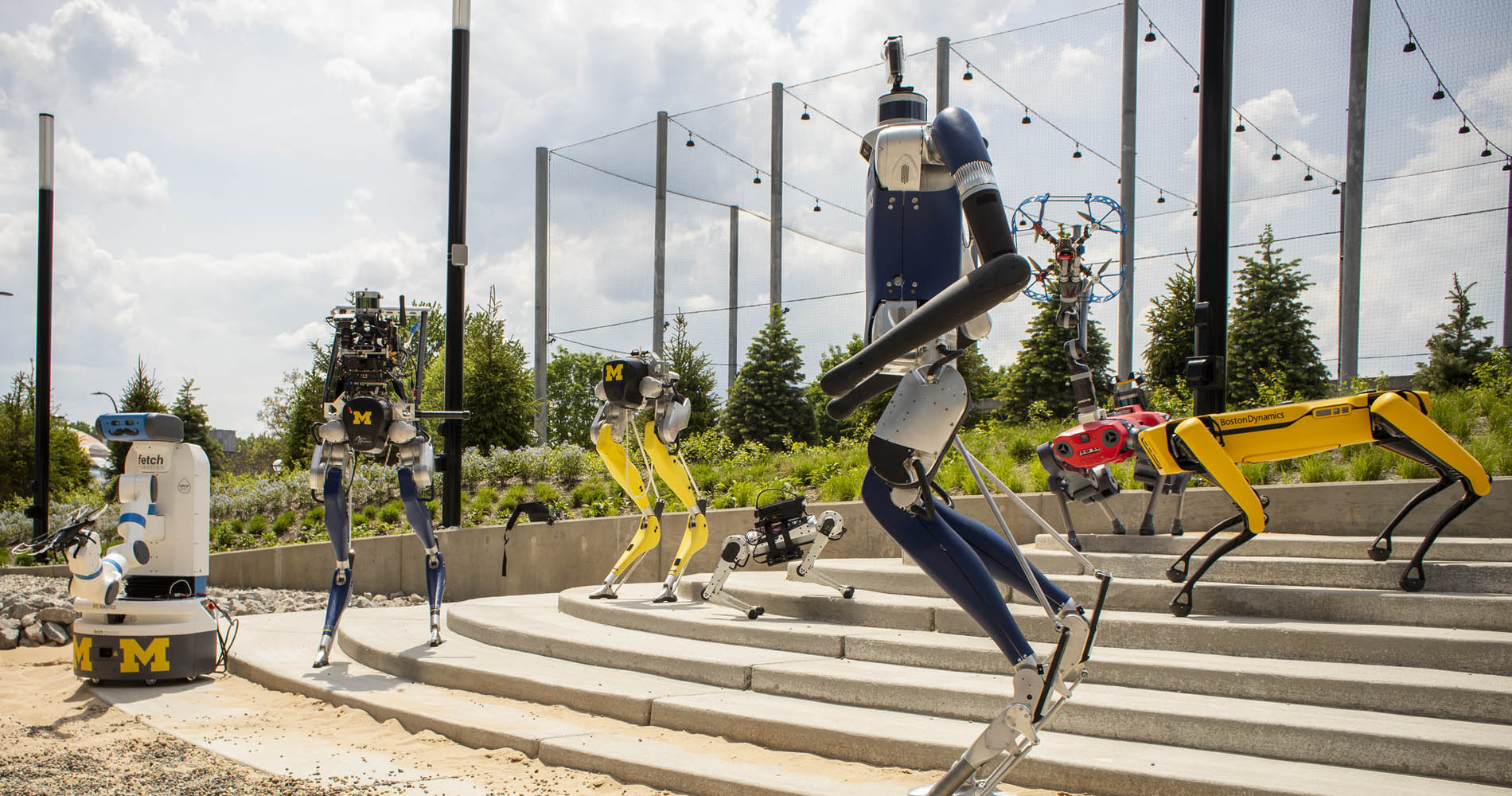 Numerous robots are organized to showcase the Robot Garden near the Robotics Institute building.