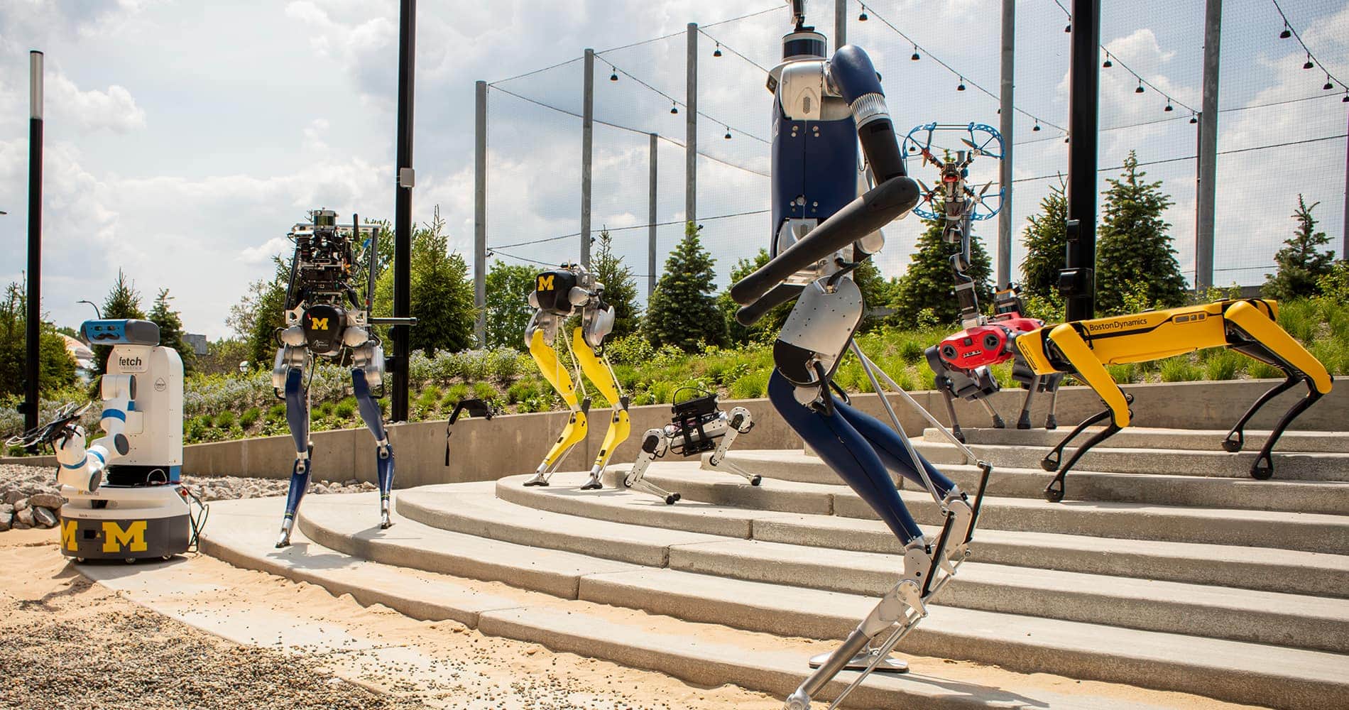 Numerous robots are organized to showcase the Robot Garden near the Robotics Institute building.