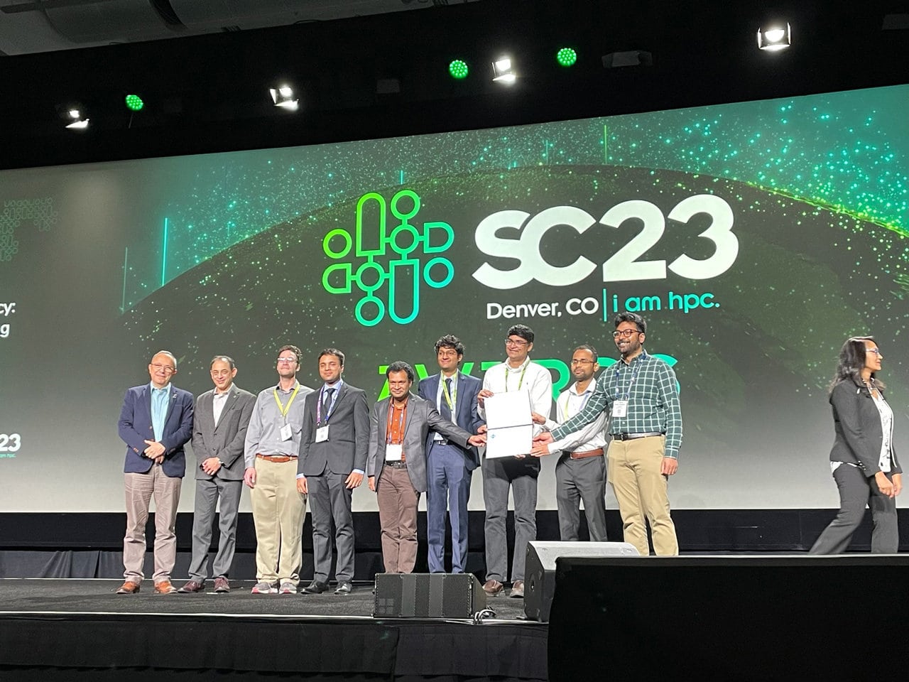 Nine men stand on stage at the conference