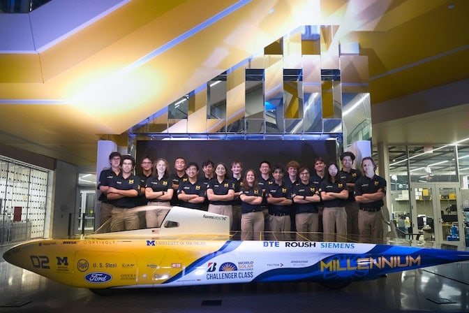 The U-M Solar Car Team stands in front of their new vehicle inside the Ford Robotics Building