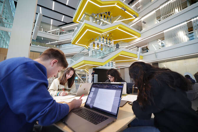 People working at a table in a modern space with a yellow zigzag staircase in the background.