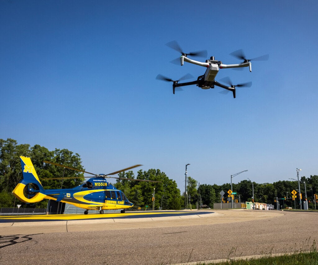 A drone hovers nearby a U-M helicopter