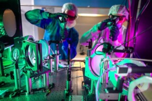 Two researchers wearing lab gear adjust the ZEUS laser system