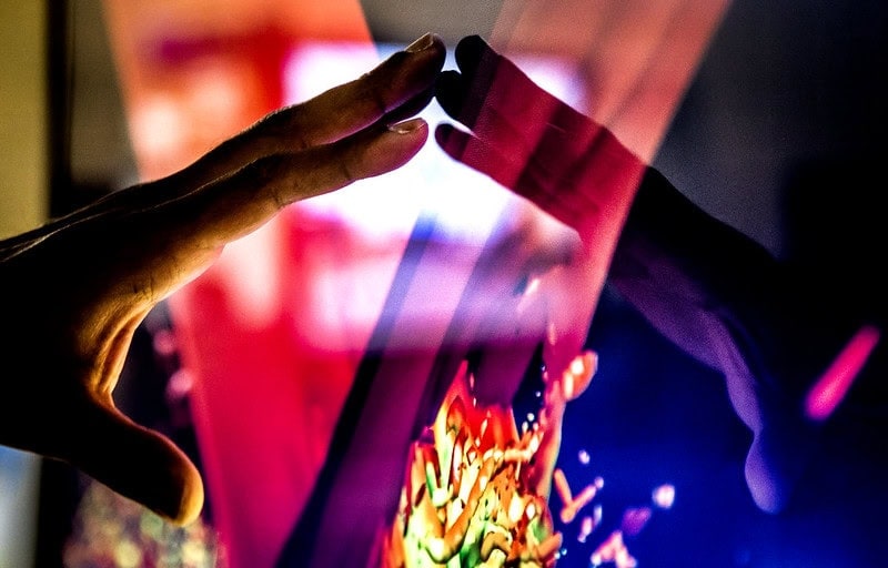 A hand gesturing over a computer model on the screen.