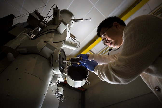 Person operating a large industrial machine with cylindrical components.