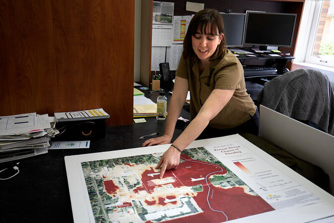 A women leans over the map showing areas of the city of Goshen, IN that are prone to flooding.