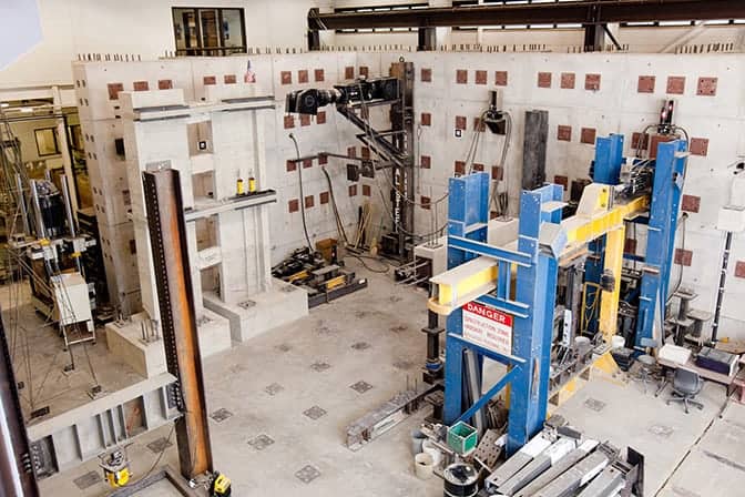 An engineering lab with structural testing equipment and metal machinery.