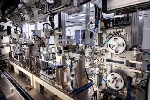 A welding and trim cutting machine at the University of Michigan’s new Battery Lab facility, featuring complex machinery in a modern industrial assembly line with metallic components and spools.