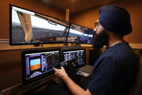 A person using a flight simulator with multiple screens and a control wheel in a room.
