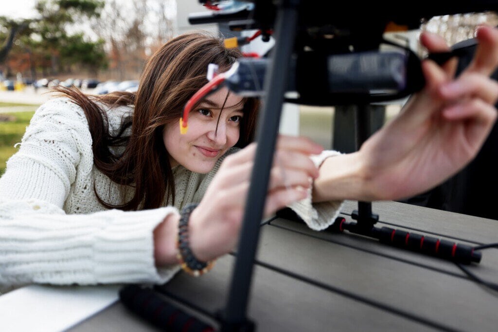 A student tinkers with wires underneath a drone